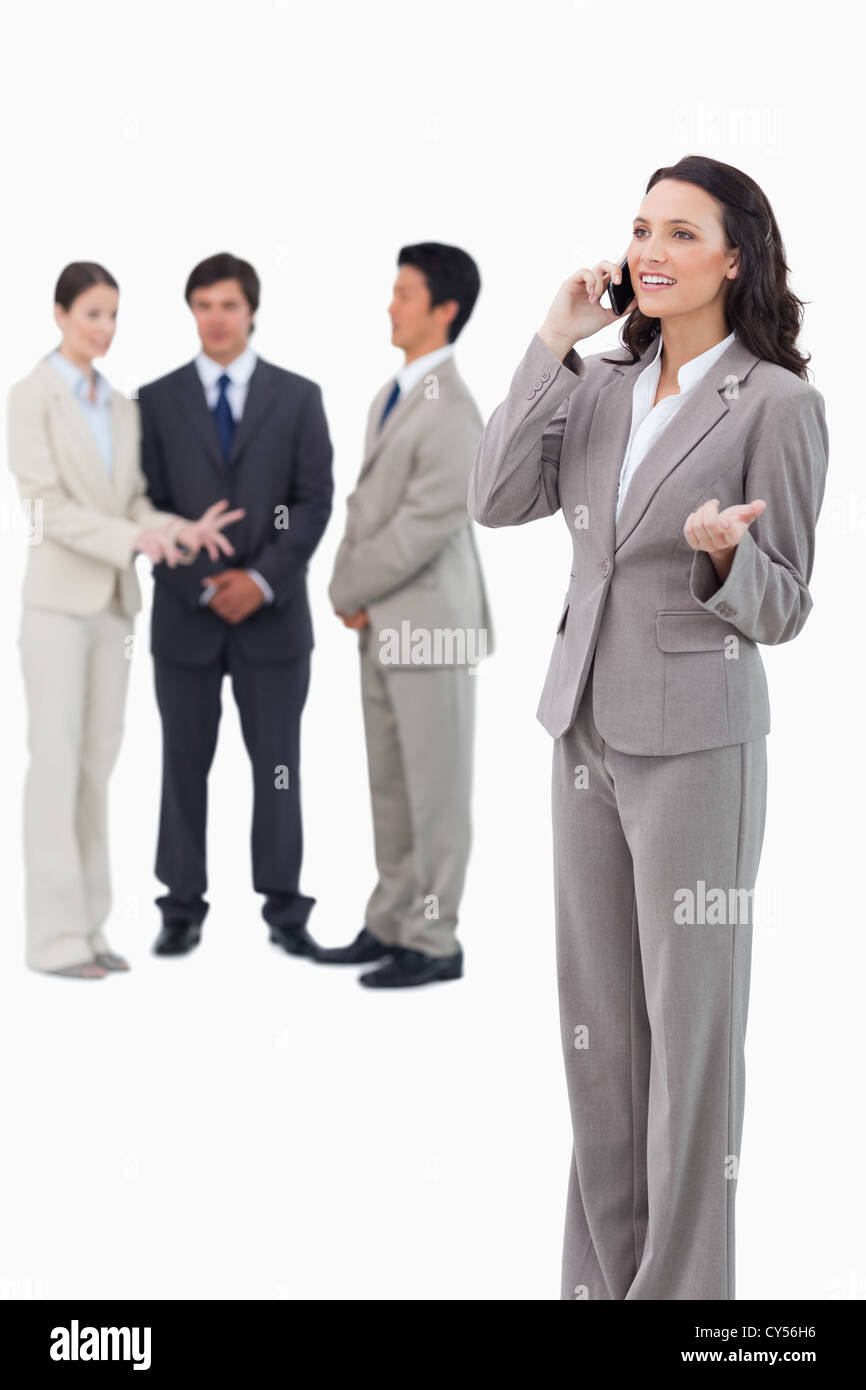 Saleswoman talking on cellphone with colleagues behind her Stock Photo ...