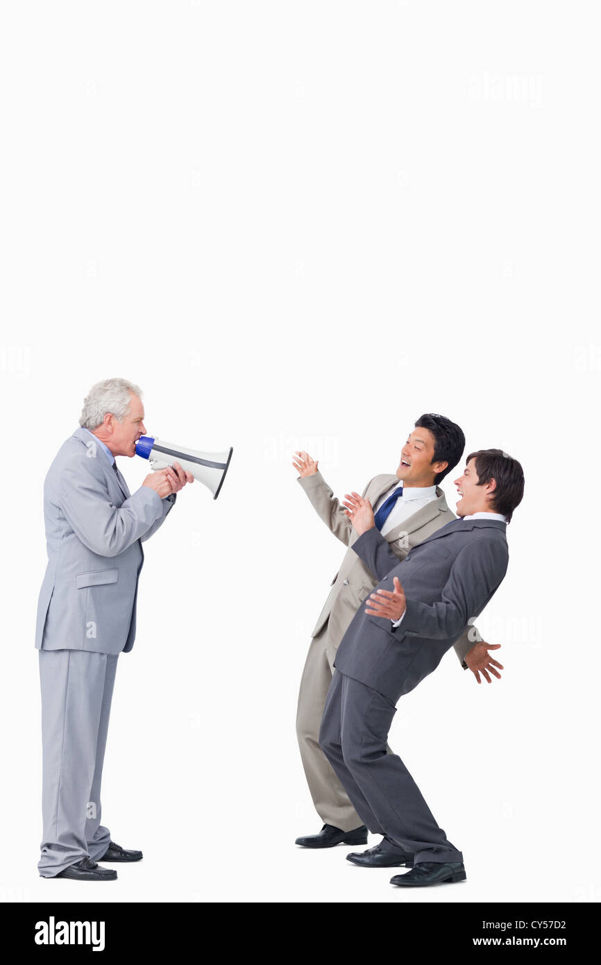 Mature businessman with megaphone yelling at his employees Stock Photo