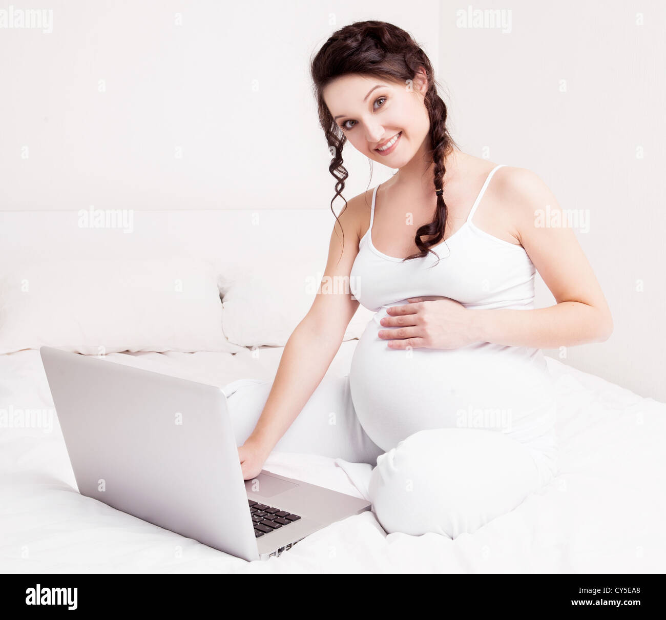 Beautiful sexy pregnant brunete woman in black lingerie holding her exposed  belly. Isolated on white background Stock Photo - Alamy