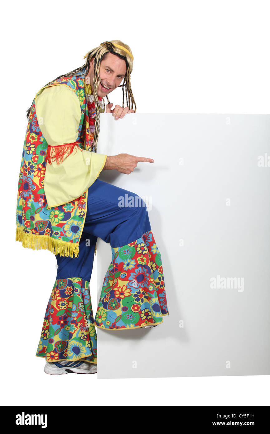 Man wearing hippy costume pointing at blank message board Stock Photo