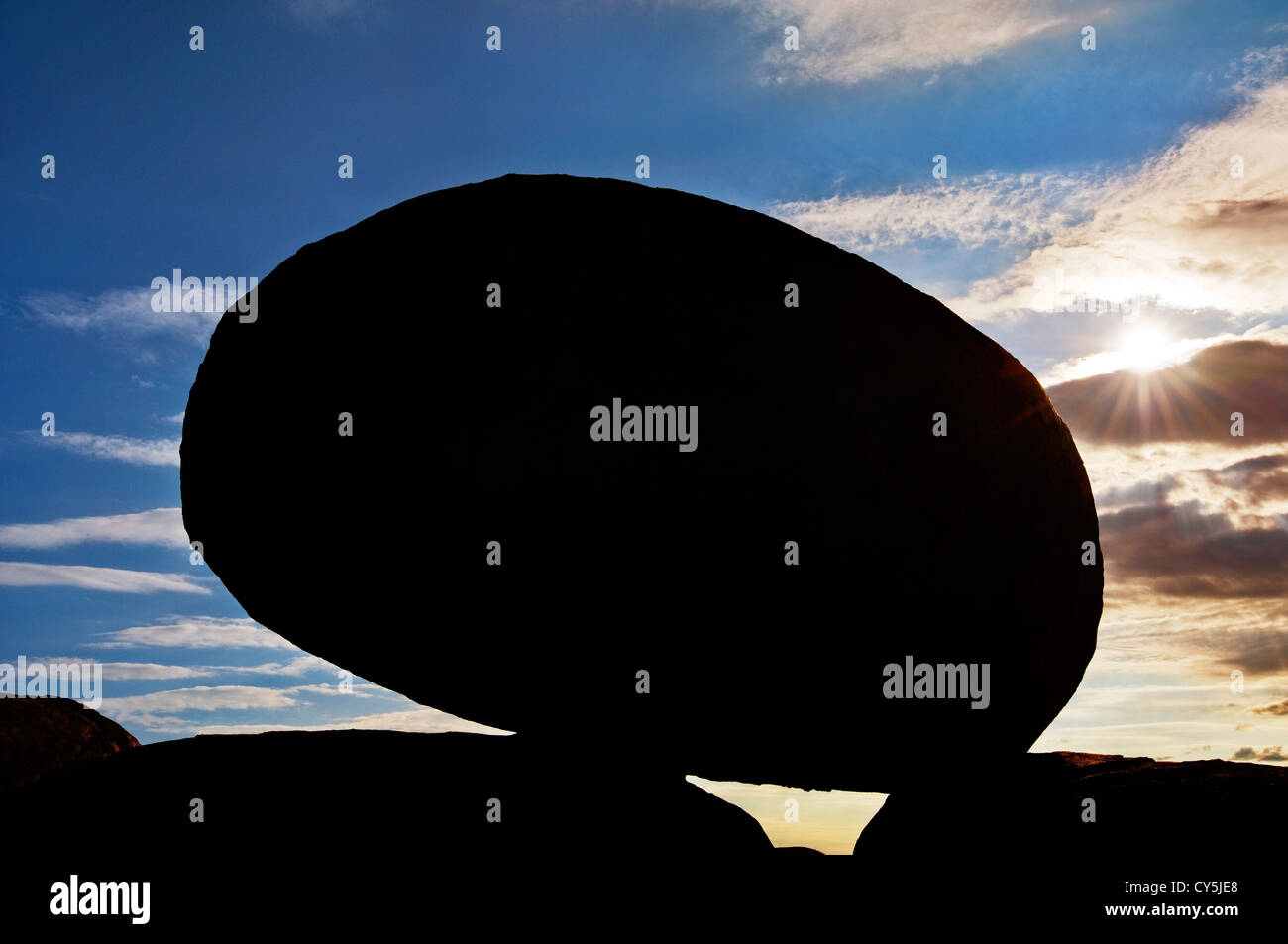Black silhouette of Devils Marbles in front of the sun. Stock Photo