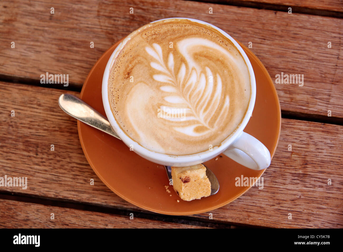 Cappuccino with leaf symbol on a wooden table Stock Photo - Alamy