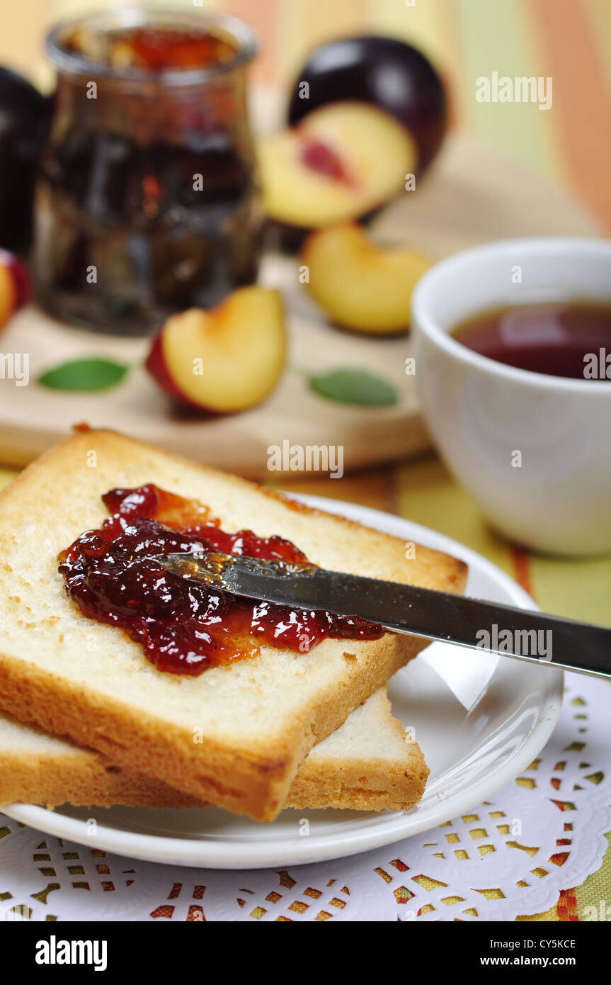 Plum jam with toast on white plate and fresh ripe plums. Small shallow dof. Stock Photo