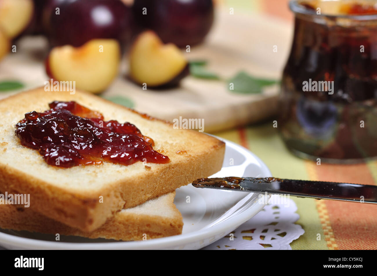 Plum jam with toast on white plate and fresh ripe plums. Small shallow dof.  Stock Photo