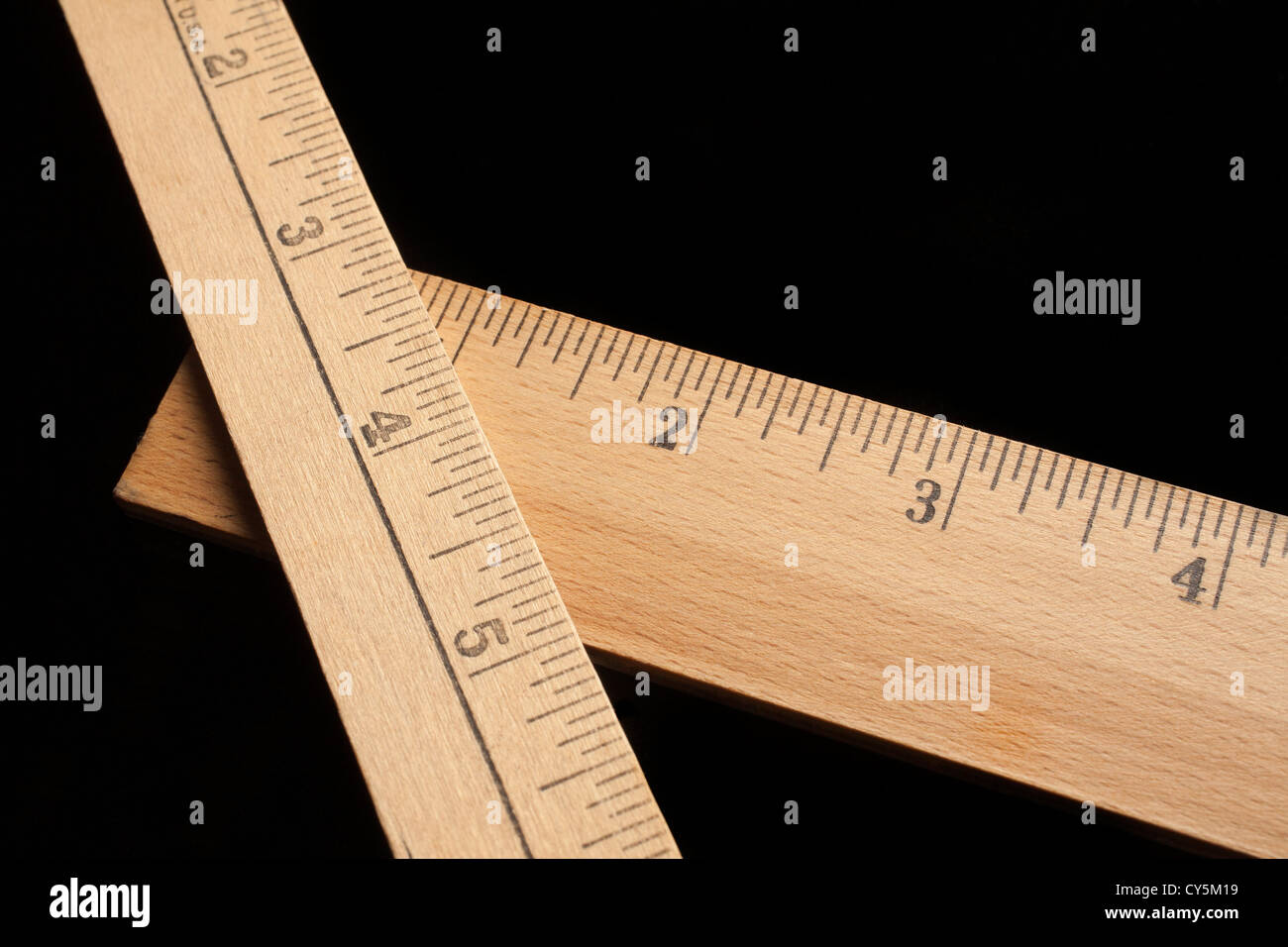 A pair of wooden rulers on a black background Stock Photo