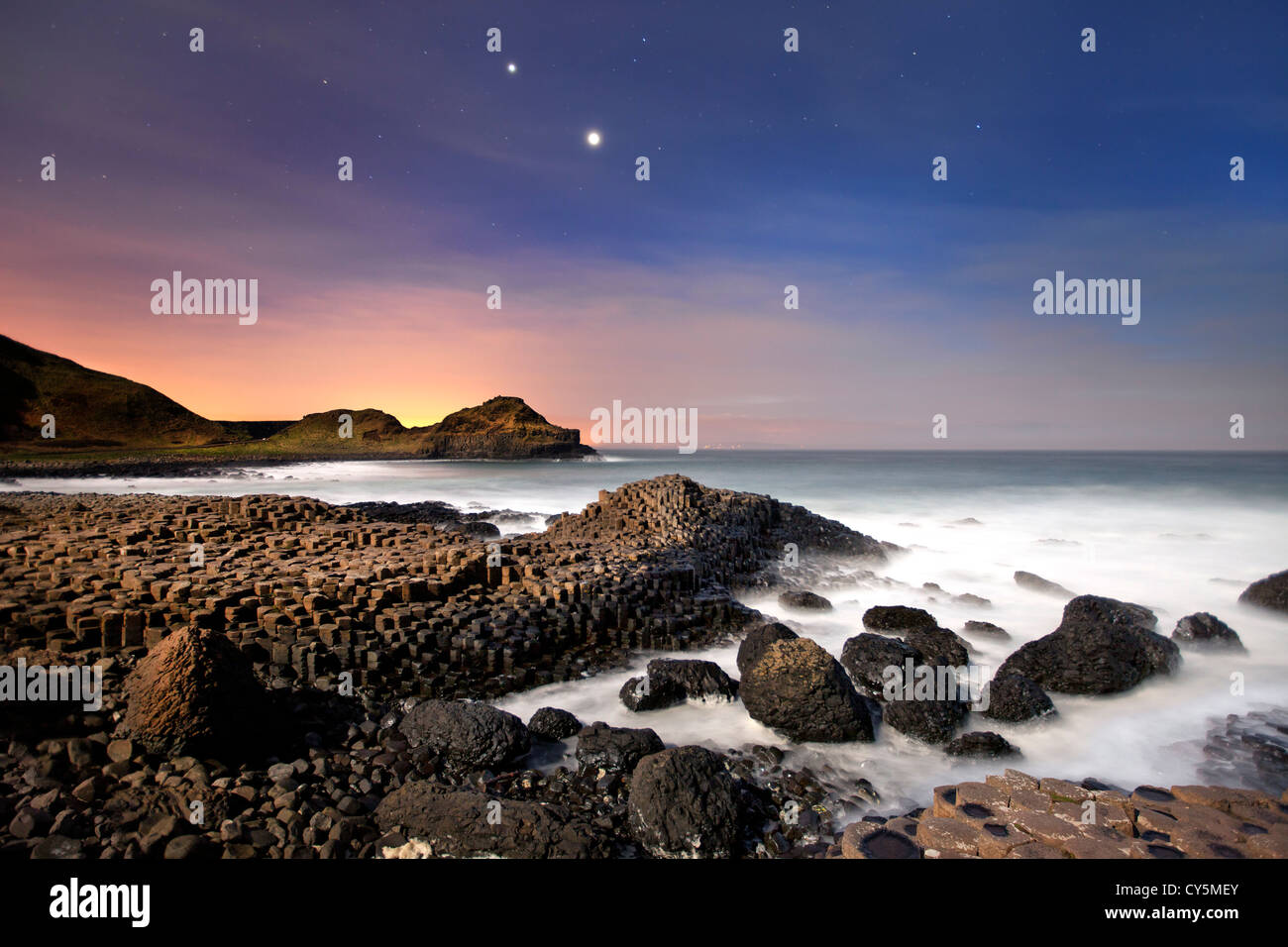 The Giants Causeway at night showing conjunction of Venus and Jupiter in sky. Stock Photo