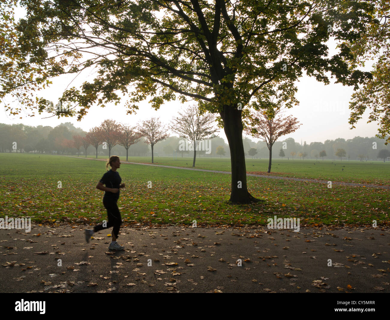 Woman running in Victoria Park, London, near 2012 Olympic site, UK Stock Photo