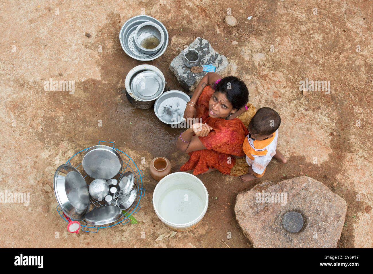 Young Indian mother and child washing dishes outside their rural indian village home. Andhra Pradesh, India Stock Photo