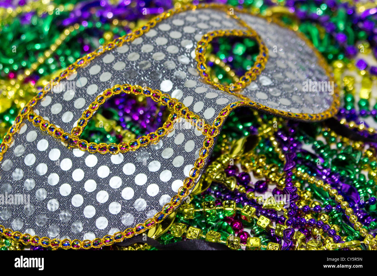 Mardi Gras masquerade mask on a background of colorful Mardi Gras Beads Stock Photo
