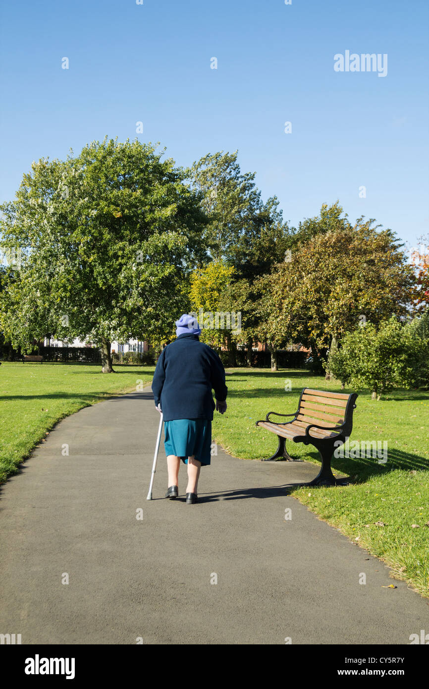 89 YEAR OLD LADY WALKING IN PARK WITH AID OF WALKING STICK IN BILLINGHAM, CLEVELAND, ENGLAND, UK Stock Photo