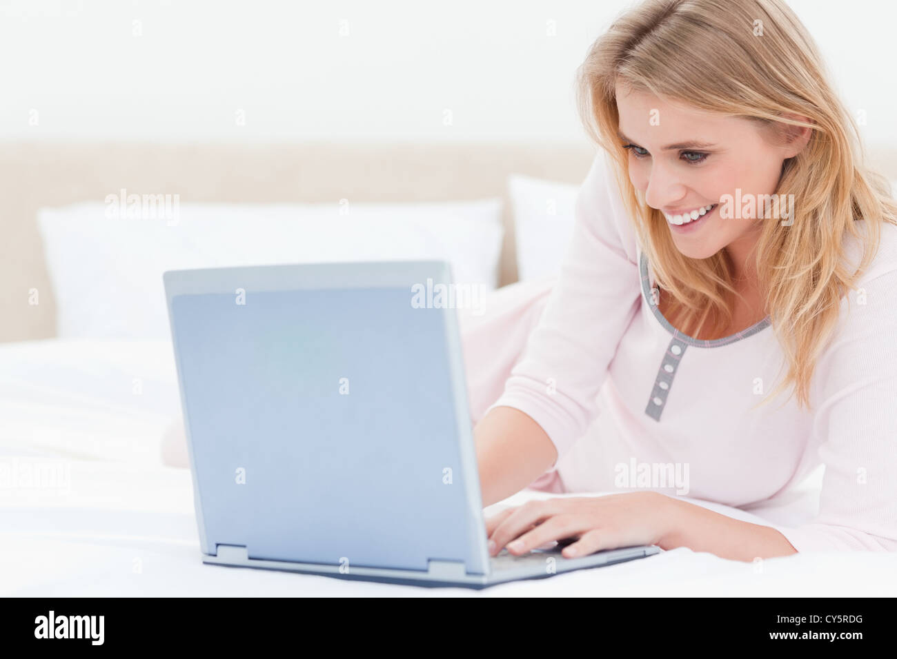 Woman lying on the bed using a laptop and smiling Stock Photo - Alamy