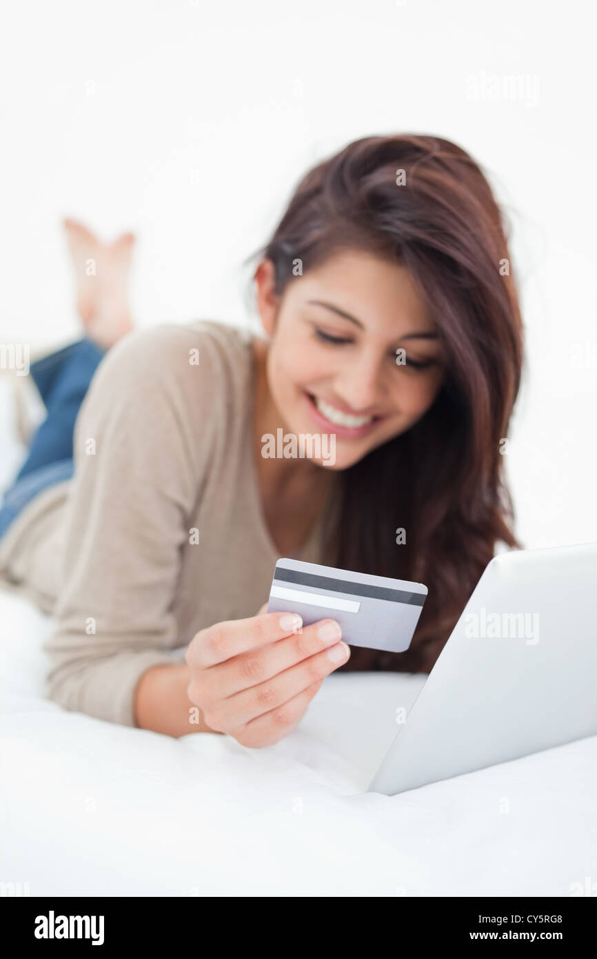 Close up, focusing on credit card, held by a smiling woman on her tablet Stock Photo
