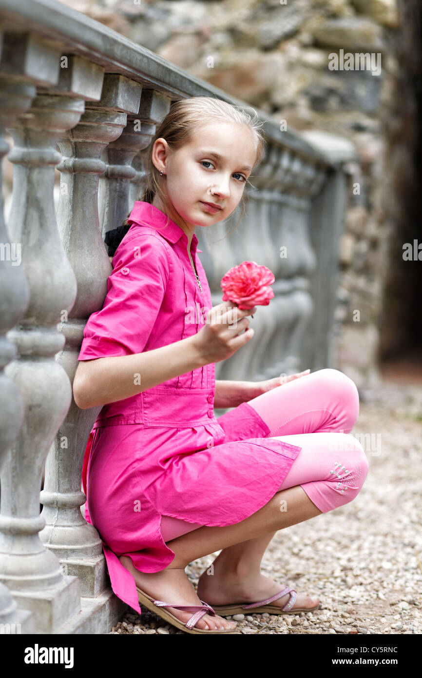 Blond girl with a flower near stone railing. Stock Photo
