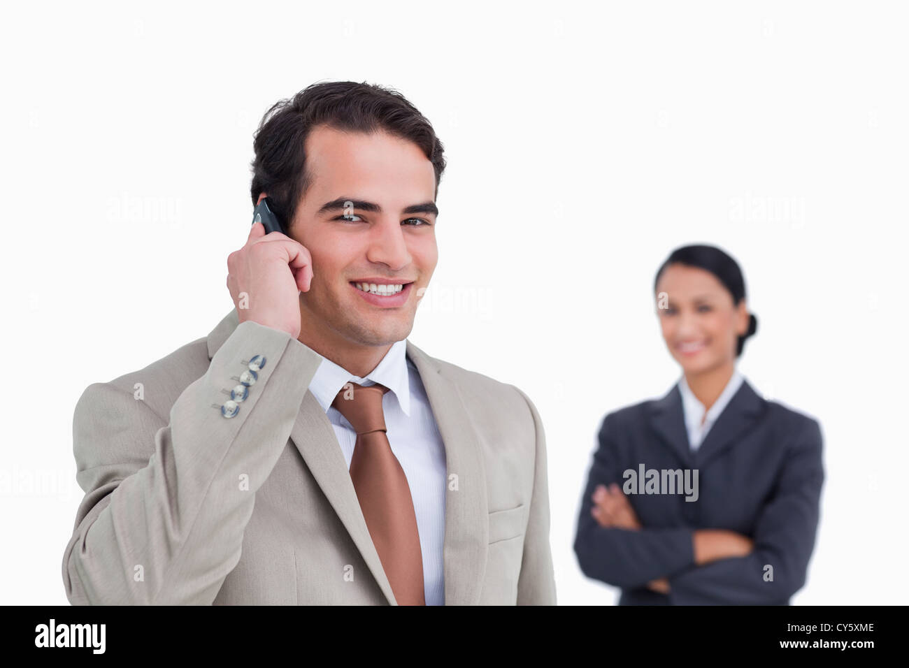 Smiling salesman on his cellphone with colleague behind him Stock Photo ...