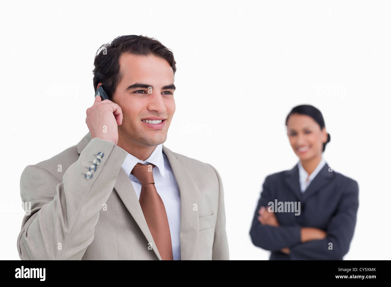 Smiling salesman on his mobile phone with colleague behind him Stock ...
