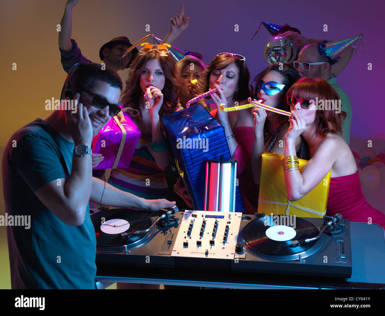 Semi Profile Of Dj Mixing Music With A Goup Of Girls Blowing Party Horns To Him Holding Presents And Other People Dancing In Stock Photo Alamy