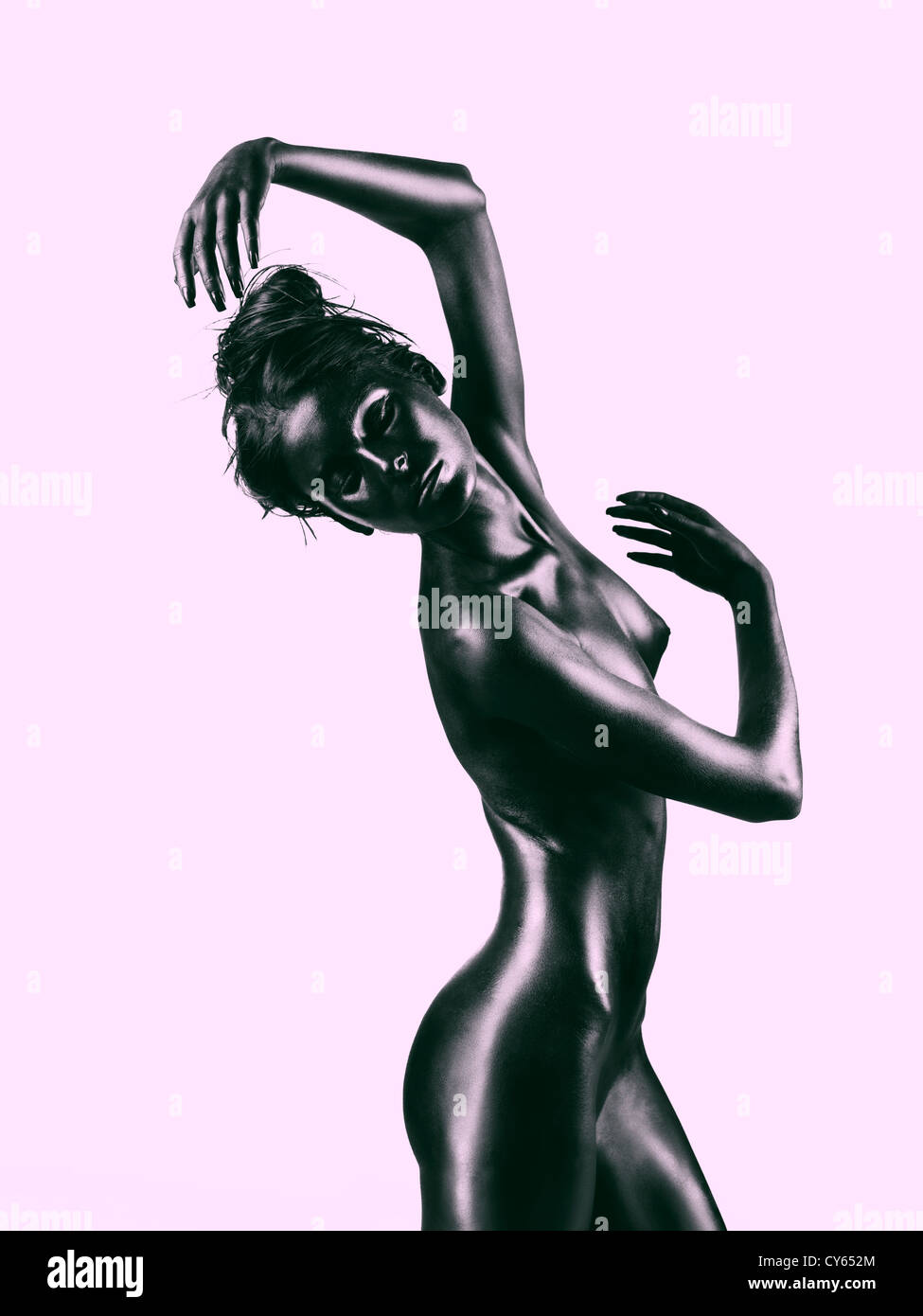 artistic nude of a young woman with black painted skin and lavander background, in a dance movement Stock Photo