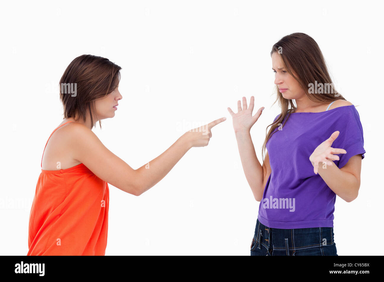 Teenage girl accusing her friend while pointing finger at her Stock Photo