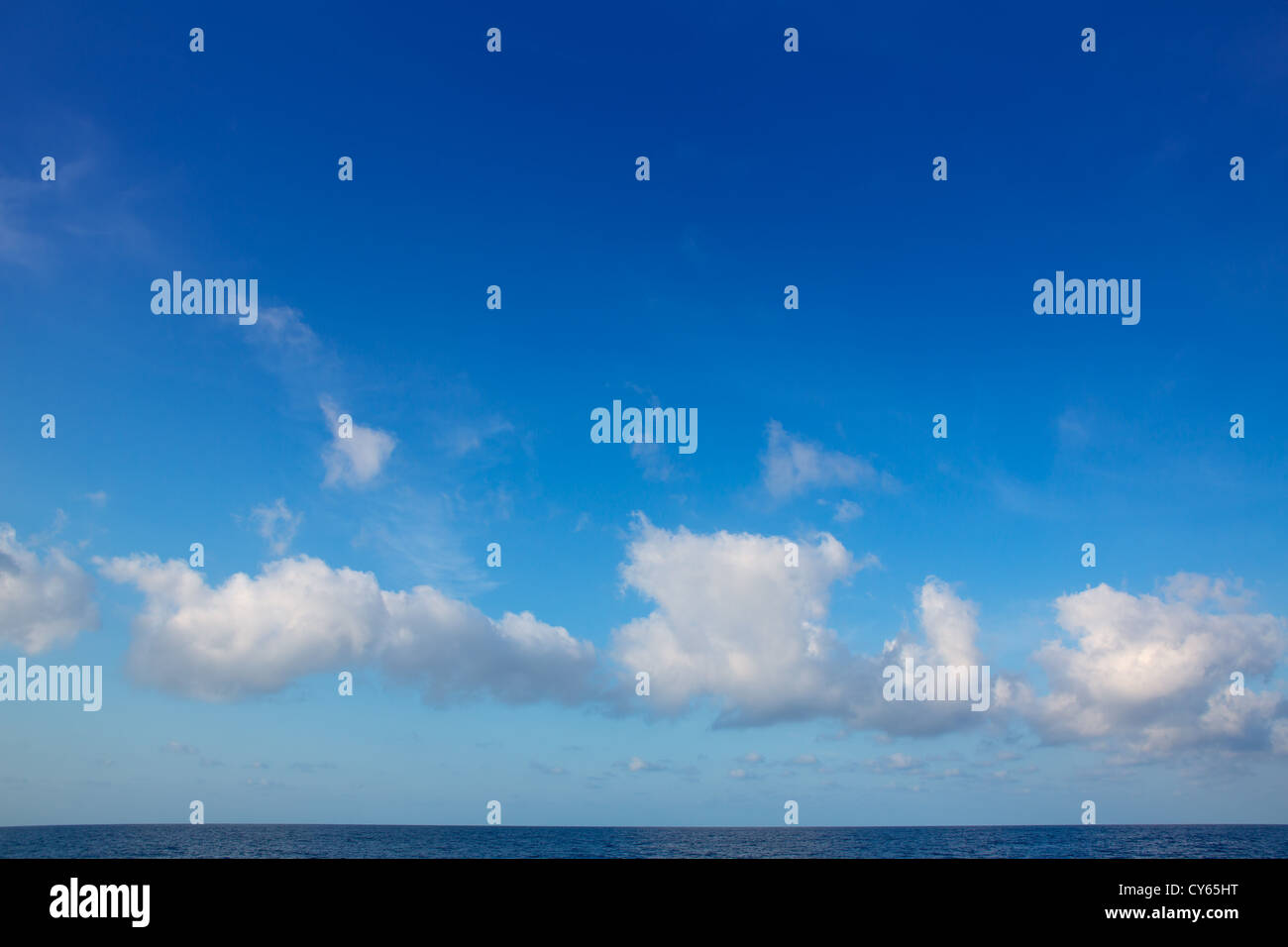 cumulus clouds in blue sky over ocean water horizon Stock Photo