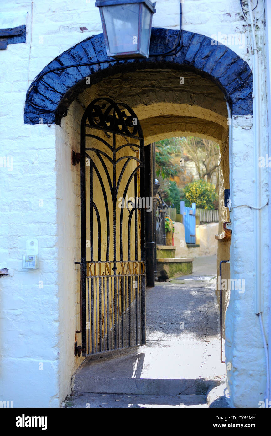 An open gated passage with an arched ceiling leading to a small court yard with a wooden gate. Stock Photo