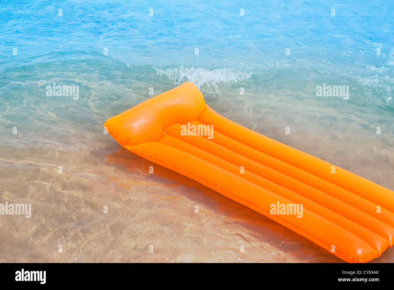 Beach shore with orange floating lounge and waves over sand bottom Stock Photo