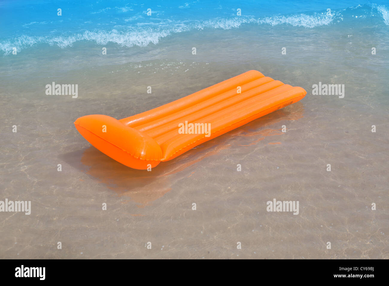 Beach shore with orange floating lounge and waves over sand bottom Stock Photo