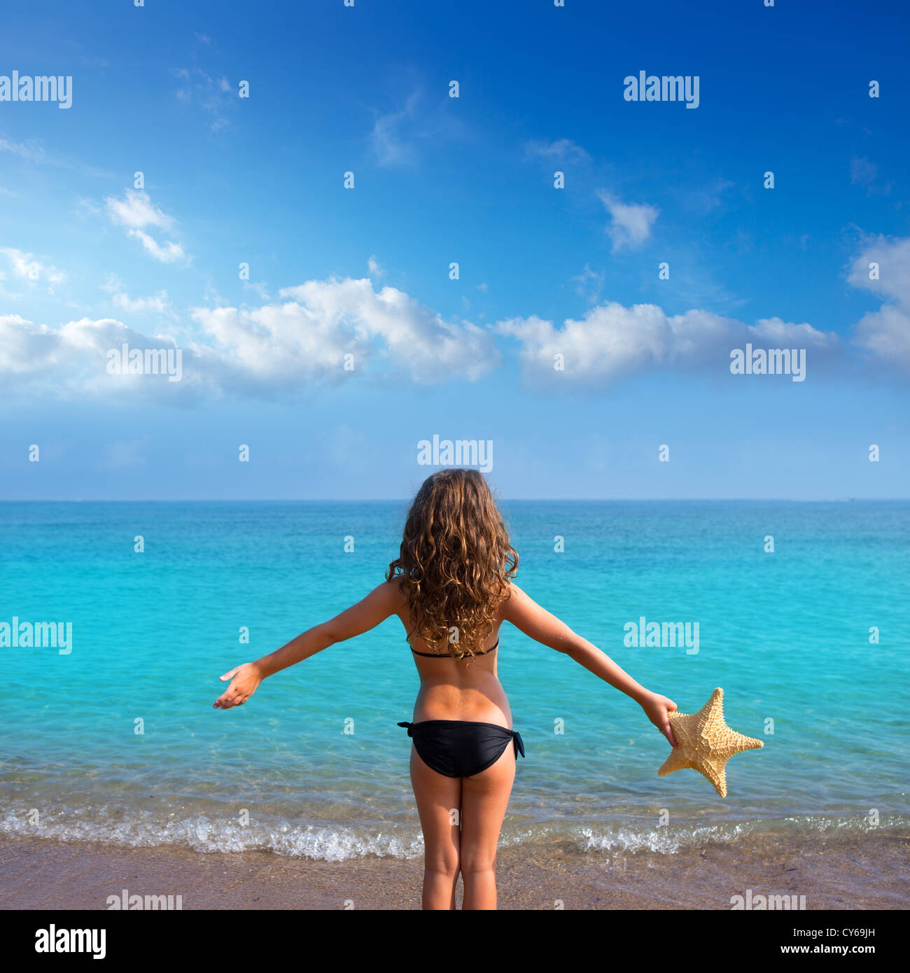 blue beach kid girl with bikini holding starfish looking sea in rear view  Stock Photo - Alamy