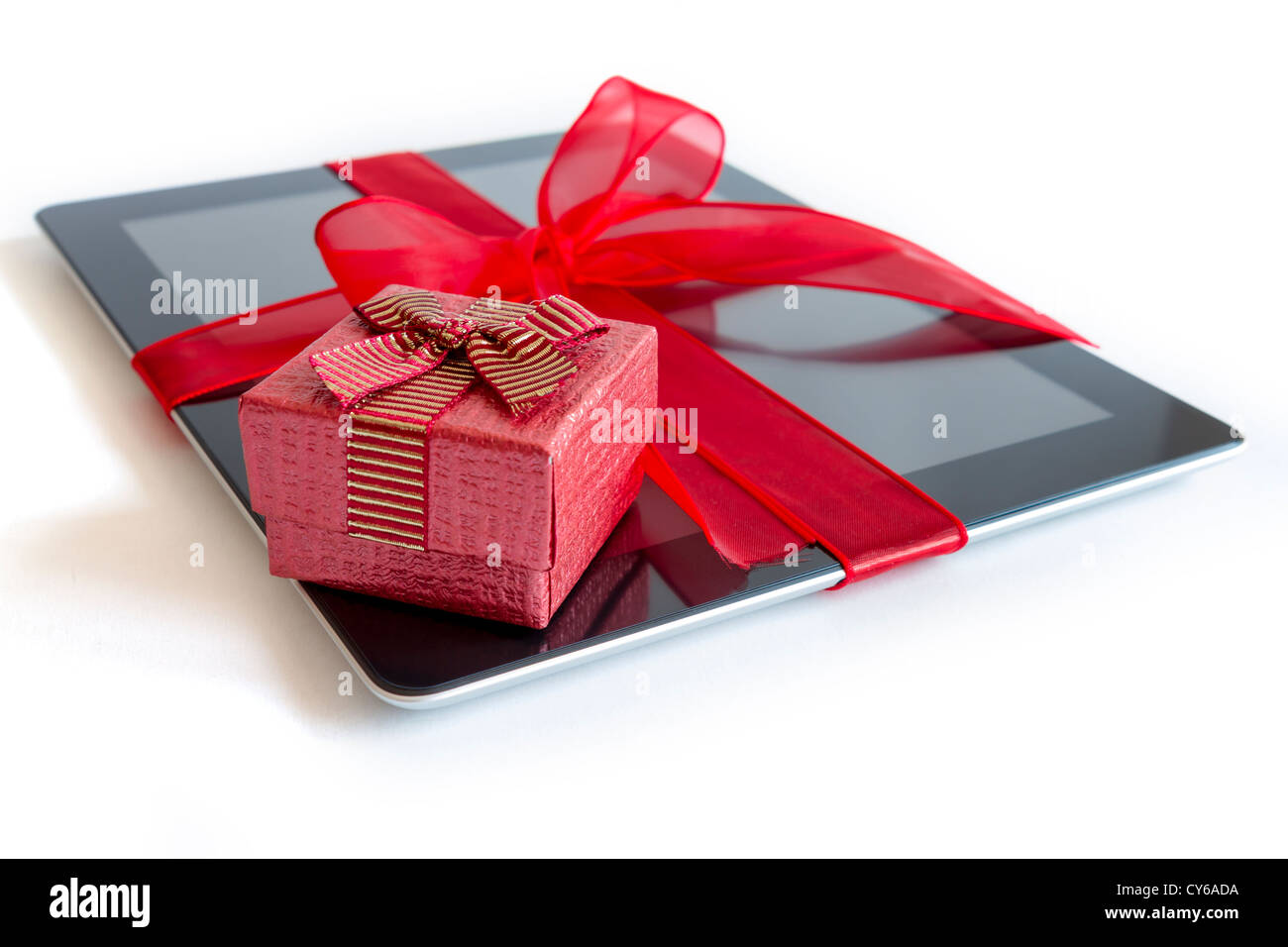 Digital tablet with red ribbon gift isolated on white. Stock Photo