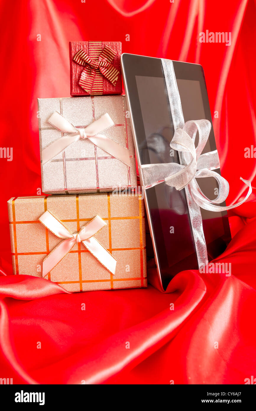 Digital tablet with christmas present on red background Stock Photo