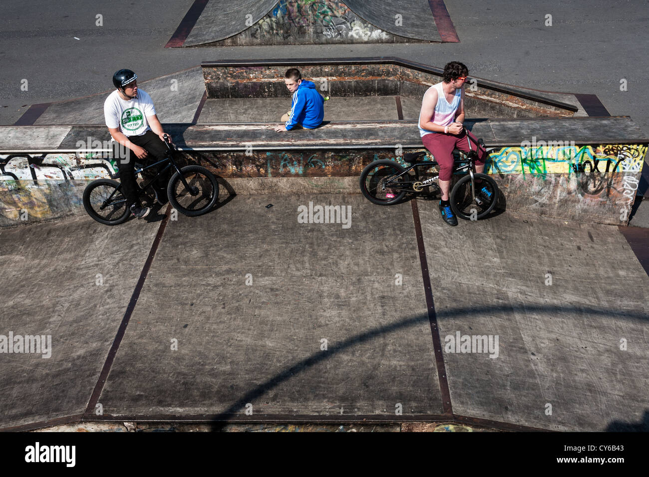 Teenagers hanging out and riding BMX bikes in a skate park by the pier