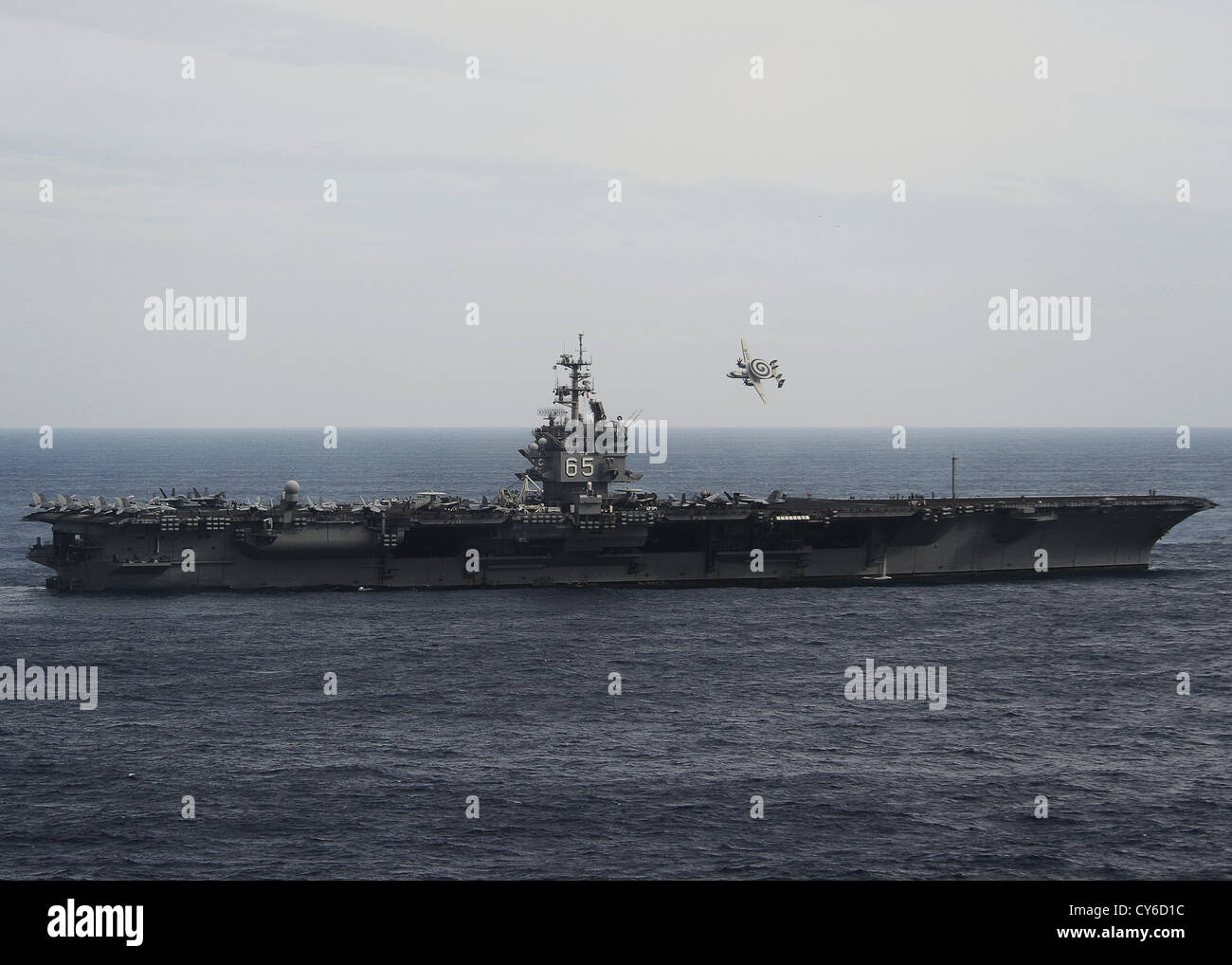 An E-2C Hawkeye assigned to the Screwtops of Carrier Airborne Early Warning Squadron (VAW) 123 flies past the aircraft carrier USS Enterprise (CVN 65) during an air power demonstration. Enterprise is completing its final deployment to the U.S. 5th and 6th Fleet areas of responsibility in support of maritime security operations and theater security cooperation efforts. The U.S. Navy has a 237-year heritage of defending freedom and projecting and protecting U.S. interests around the globe. Stock Photo