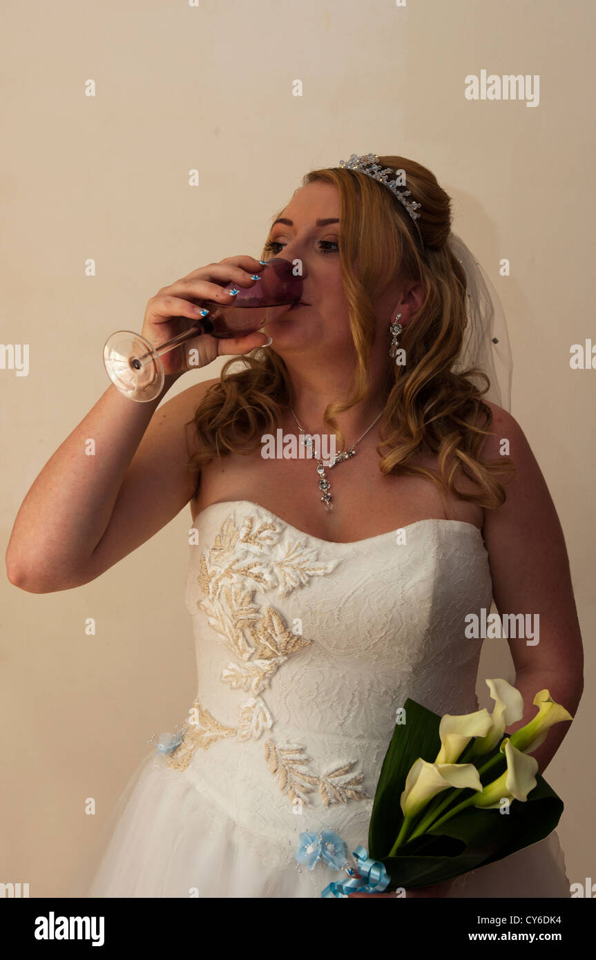 Model Released bride having a drink to calm her nerves before the wedding Stock Photo