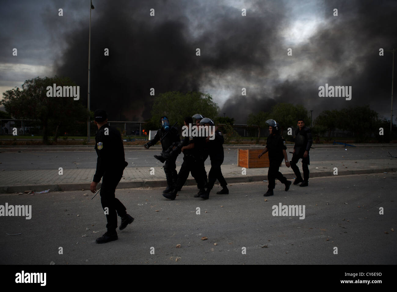 Police carry a wounded colleague to safety during the storming of the US embassy in Tunis Stock Photo