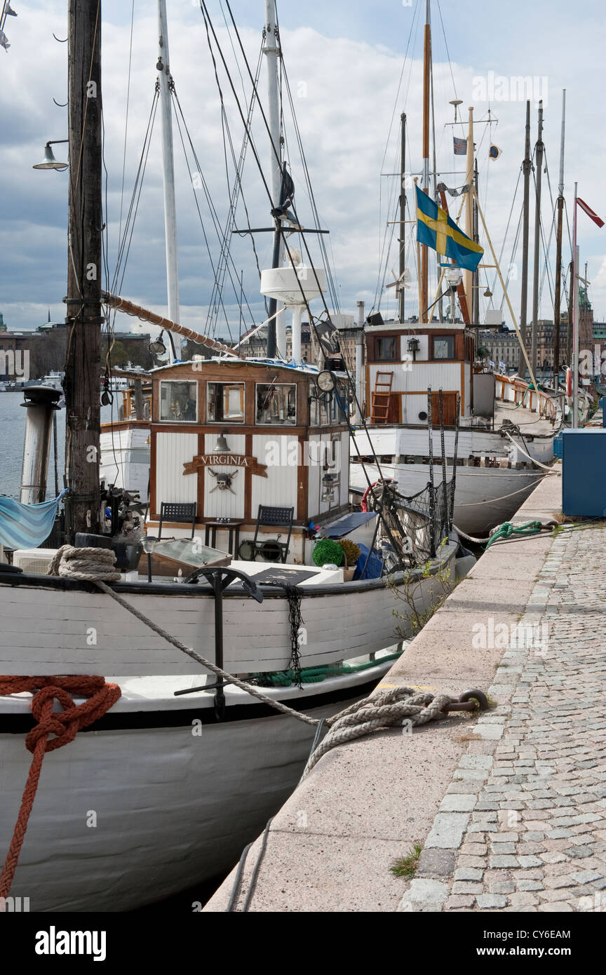 Historic fishing and sailing boats moored along the quayside of Strandvagen street in central Stockholm Stock Photo