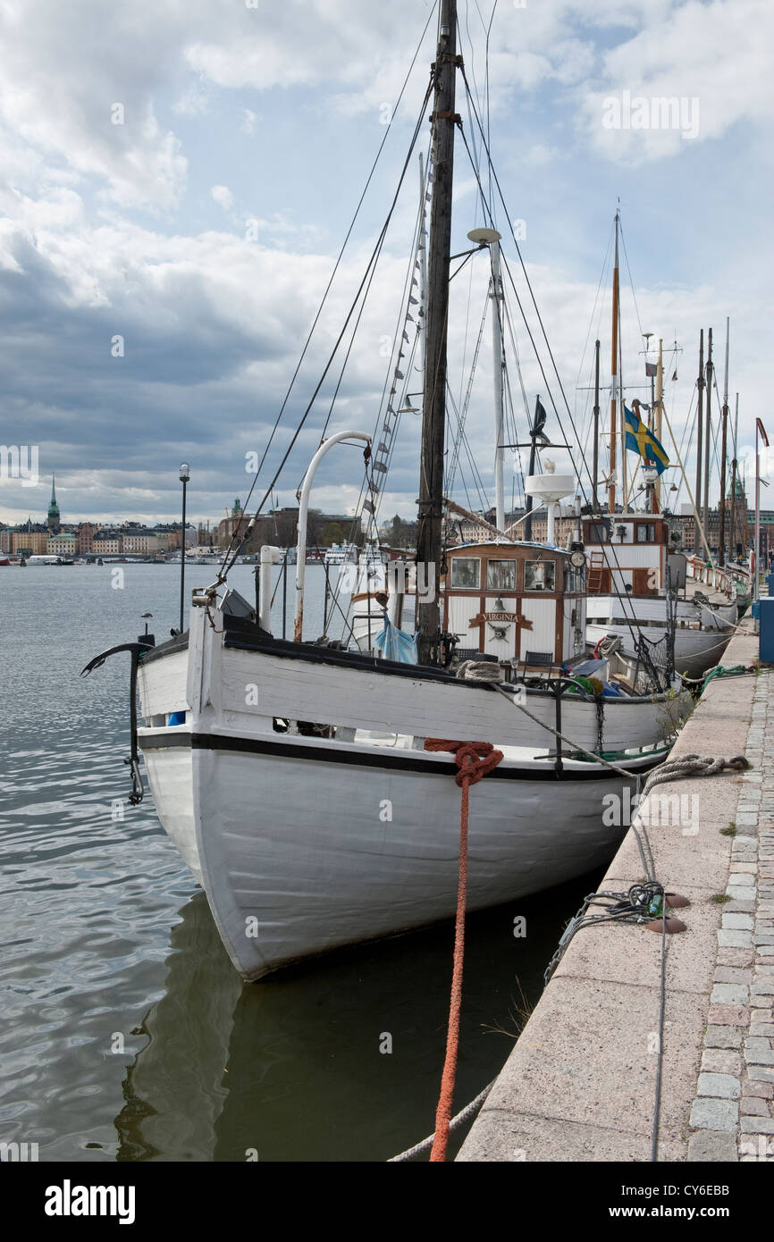 Historic fishing and sailing boats moored along the quayside of Strandvagen street in central Stockholm Stock Photo