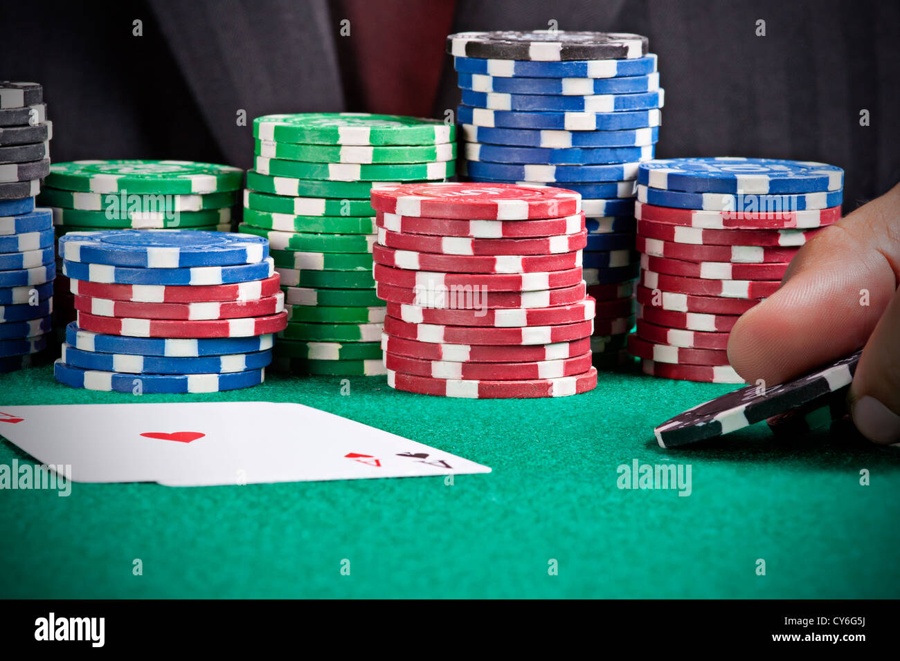 A man playing poker and raising his bet with two black chips Stock Photo