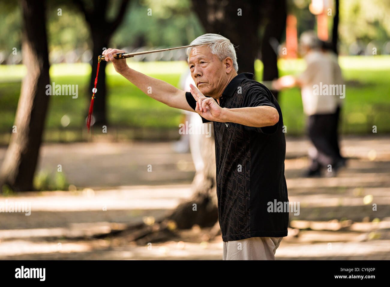 An elderly Chinese man practices martial arts sword exercise early