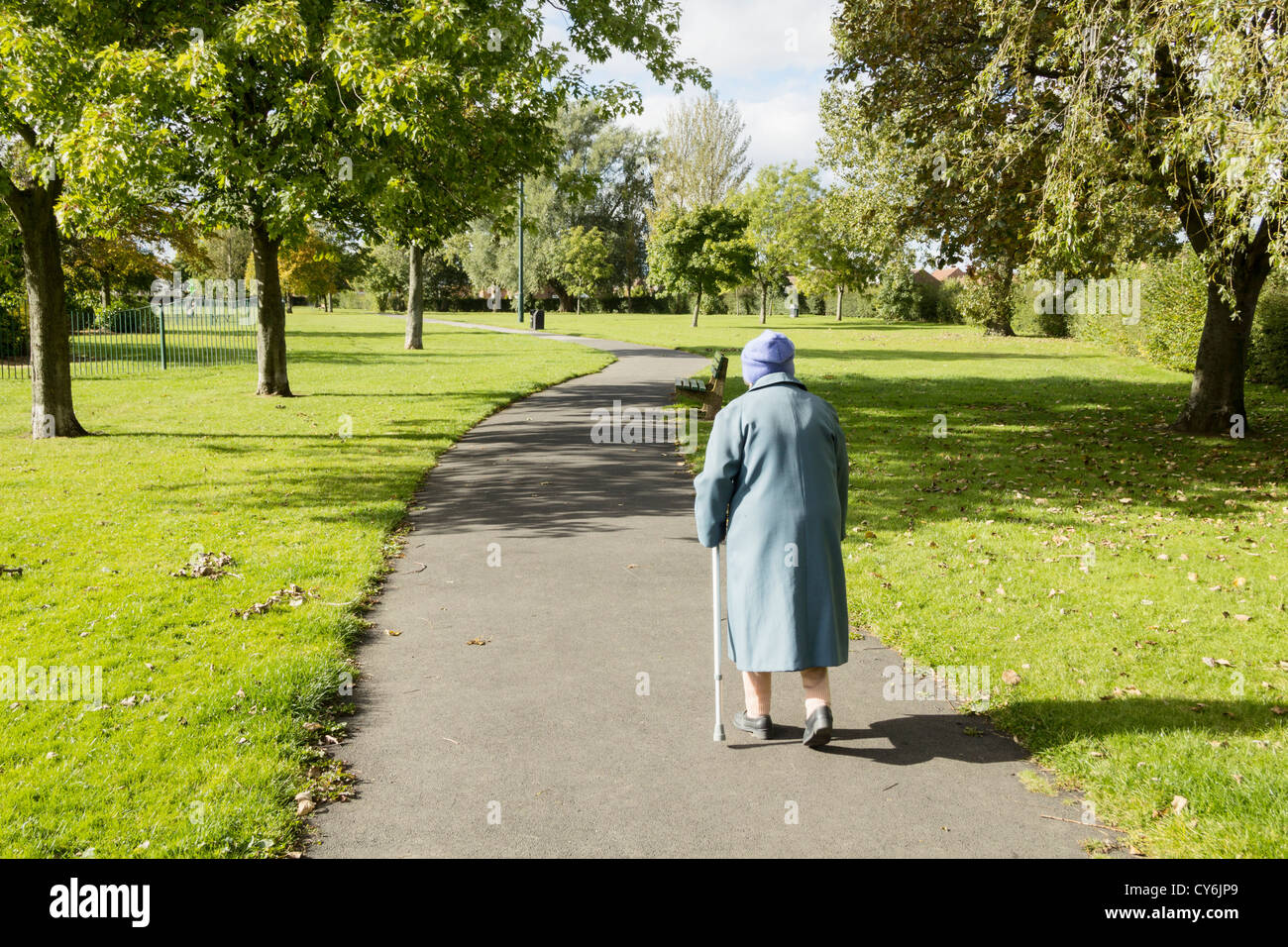 89 YEAR OLD LADY WALKING IN PARK WITH AID OF WALKING STICK IN BILLINGHAM, CLEVELAND, ENGLAND, UK Stock Photo