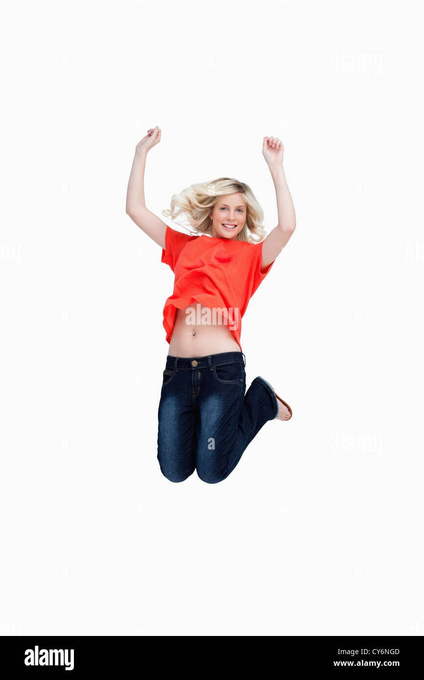 Dynamic teenager energetically jumping while raising her arms above the head Stock Photo