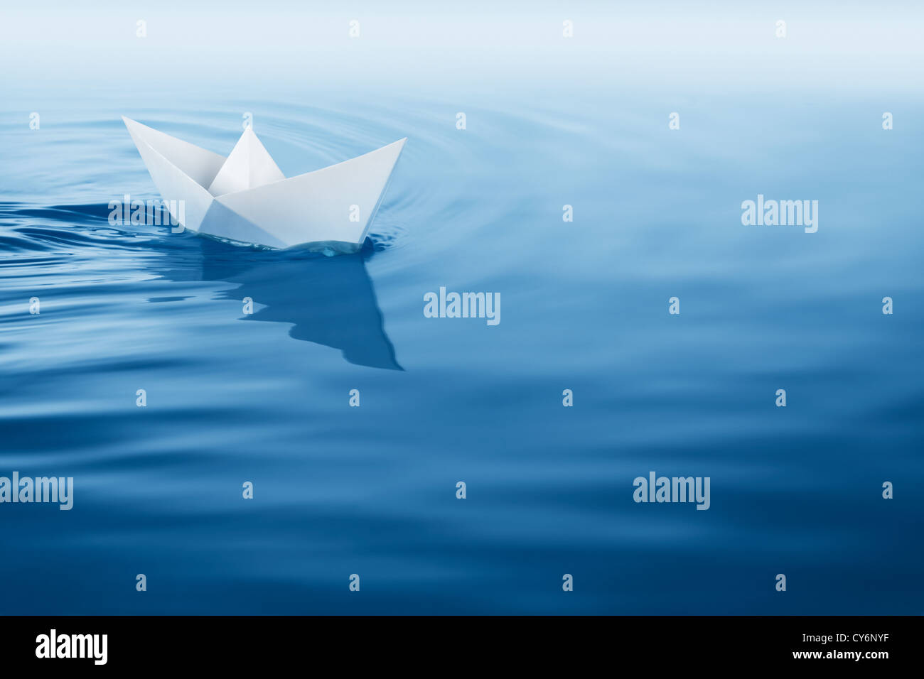 paper boat sailing on blue water surface Stock Photo