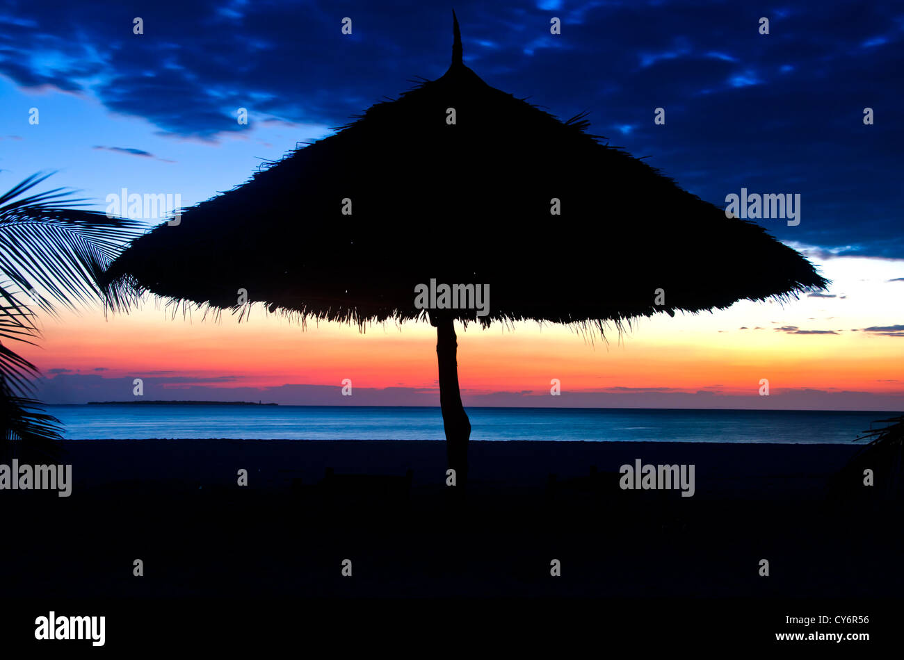 Silhouette of Parasol on a the Beach over Sunset with cloudy sky Stock Photo