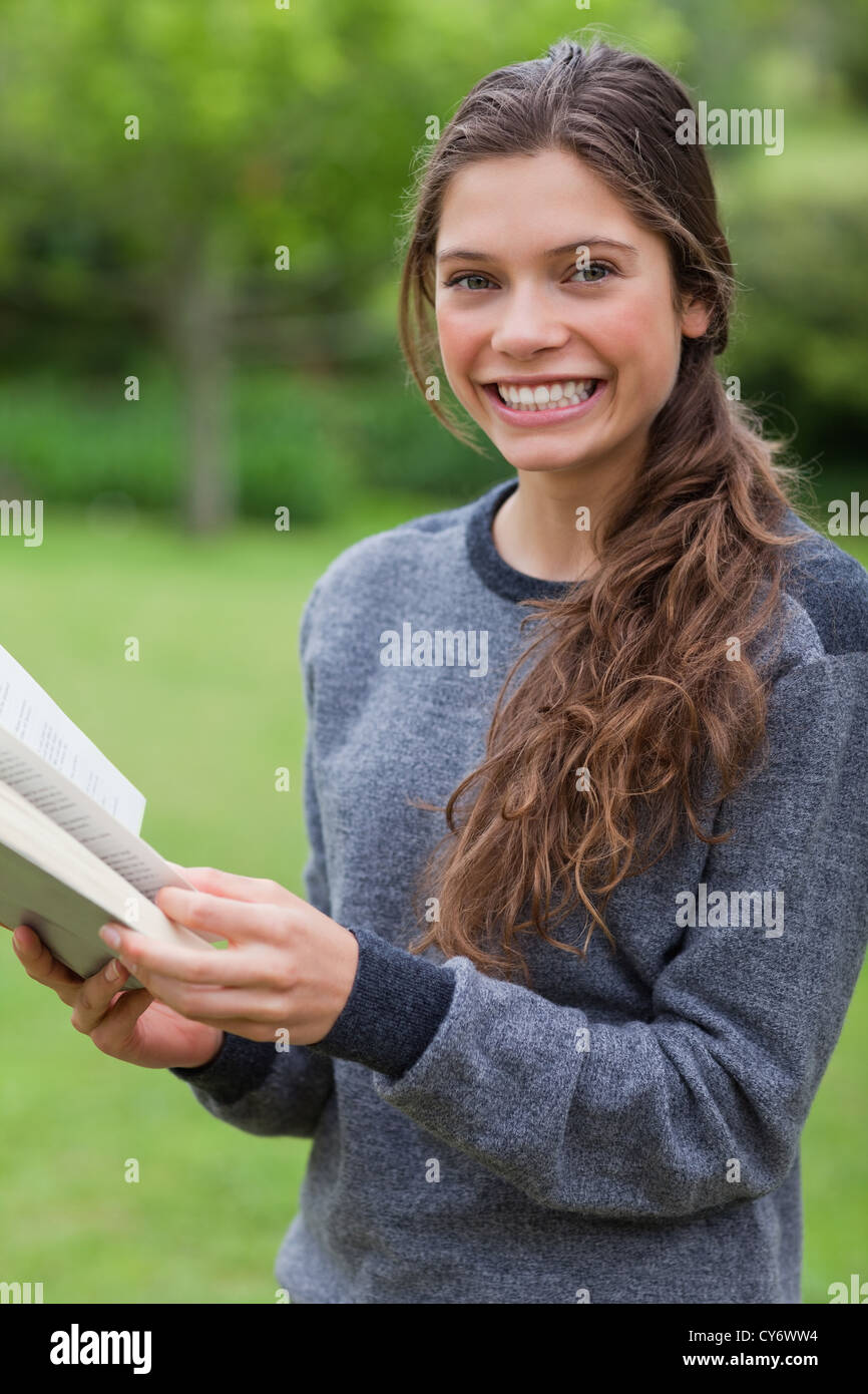 Young smiling girl looking at the camera while reading a book Stock