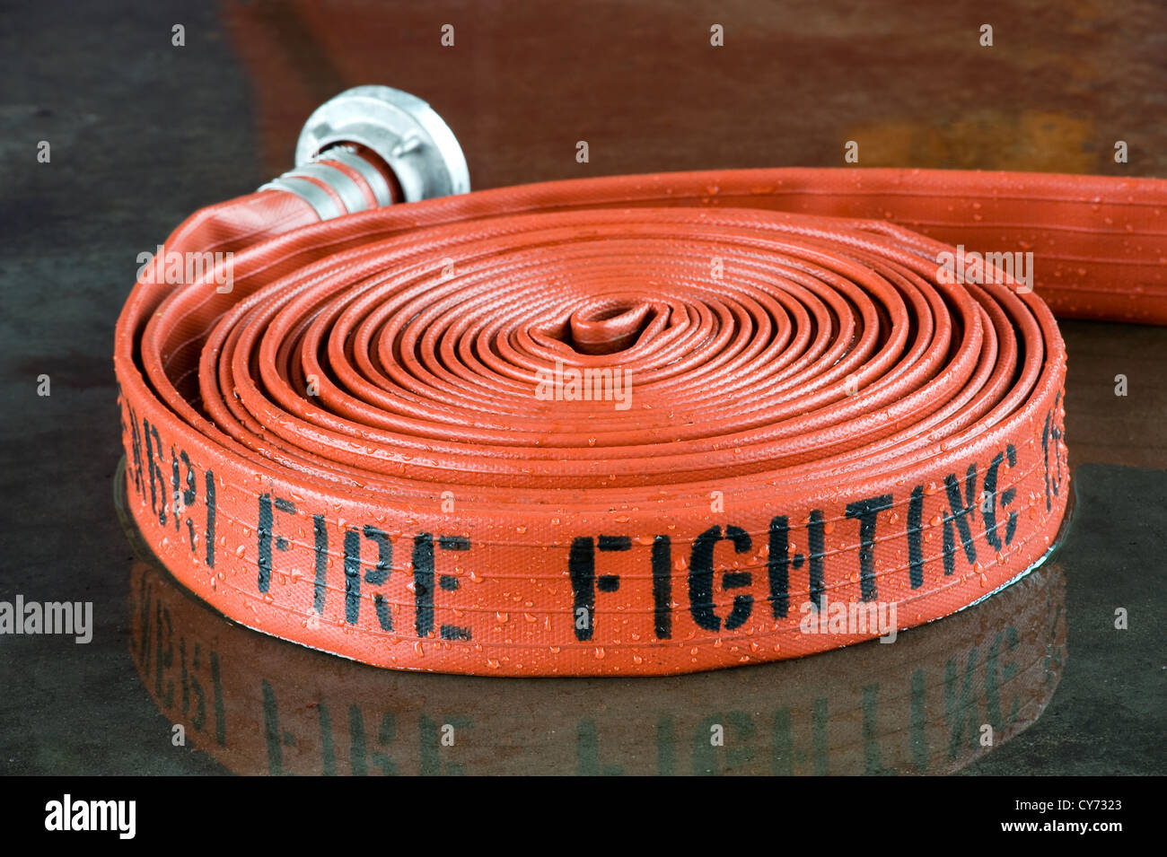 A rolled up firehose on the wet floor in a firestation used by firefighters Stock Photo