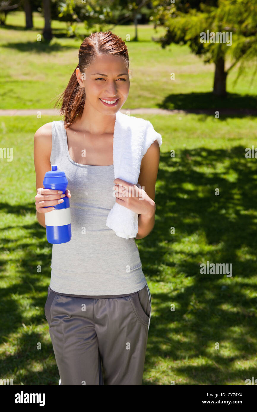 Woman smiling while holding a sports bottle and a towel Stock Photo - Alamy