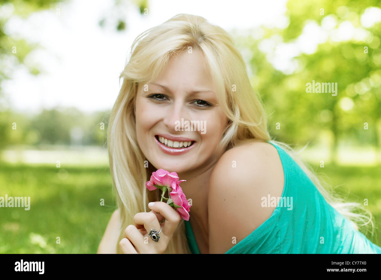 Portrait of beautiful and smiling blond woman relaxing in the park ...