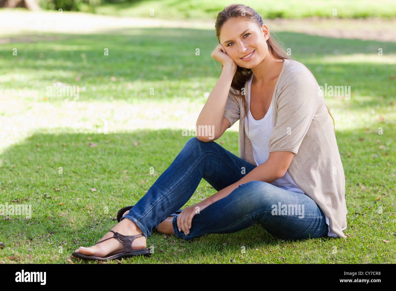 Smiling woman sitting on the grass Stock Photo - Alamy