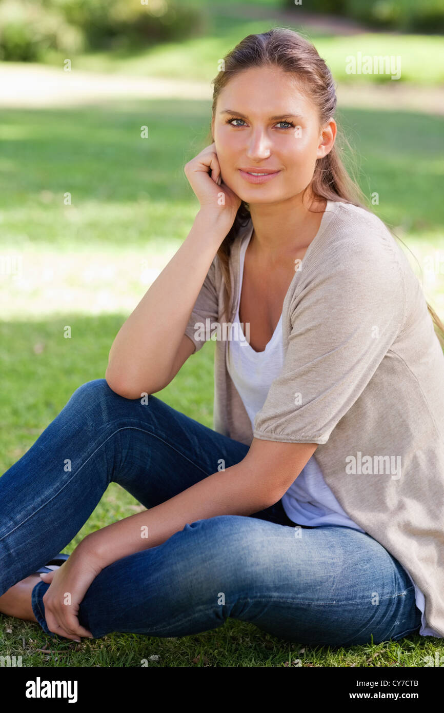 Thoughtful woman sitting on the lawn Stock Photo - Alamy