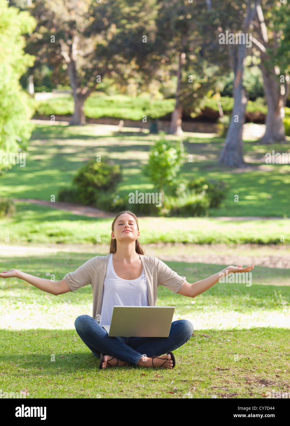 Woman sitting on the lawn in a yoga position with a laptop Stock Photo ...