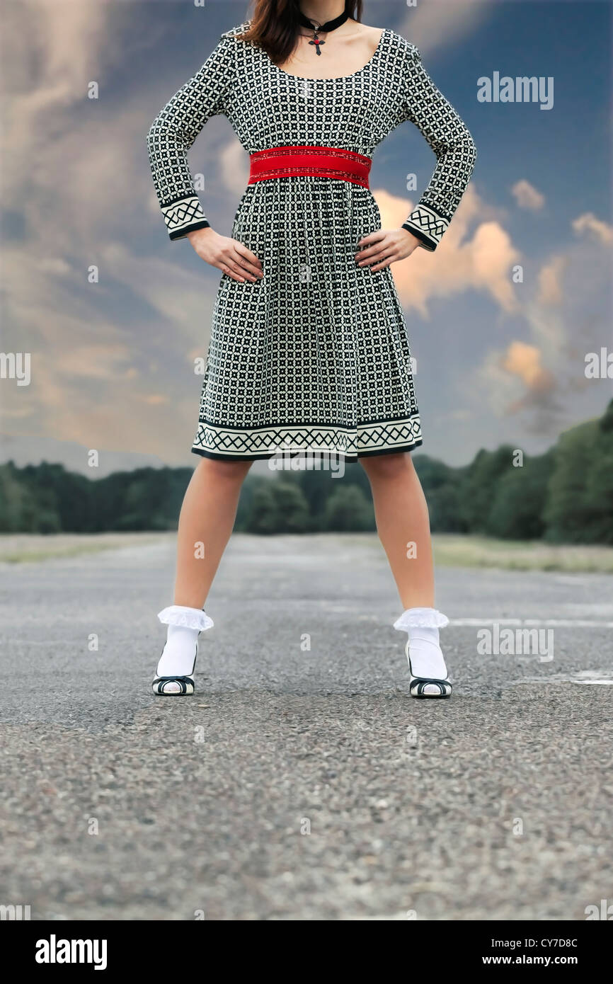 a woman in a black and white dress is standing on a street Stock Photo