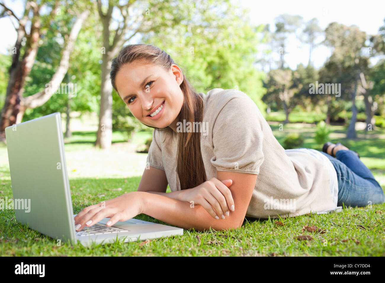 Smiling woman lying on the lawn with her laptop Stock Photo - Alamy